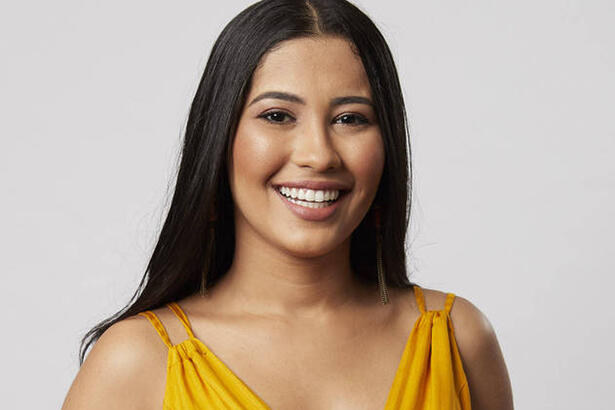 Thaynara OG sorrindo, de vestido amarelo, durante gravação de campanha publicitária