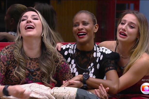 Amanda, Aline Wirley, e Bruna Griphao sentadas no sofá conversando com Tadeu Schimidt e sorrindo por estarem na final do BBB 23