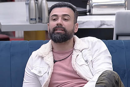 Bruno Tálamo sentando no sofá da sala do A Grande Conquista