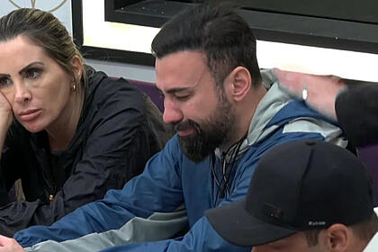Bruno Tálamo chorando sentado na mesa de A Grande Conquista e sendo consolado por colegas