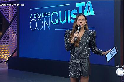 Mariana rios em frente ao telão, em trecho da estreia do reality a grande conquista