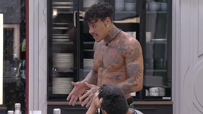Murilo Dias, sem camisa, gesticulando com as mãos durante conversa na cozinha do A Grande Conquista