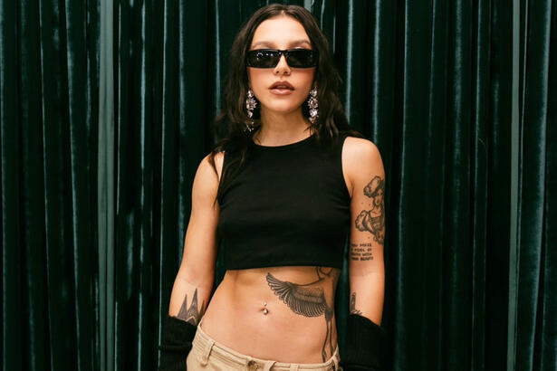 Priscilla Alcantara de top preto e calça bege, usando oculos de sol durante bastidores