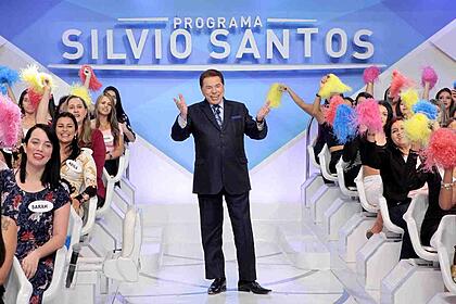 Silvio santos levanta os braços e anima a plateia do programa silvio santos