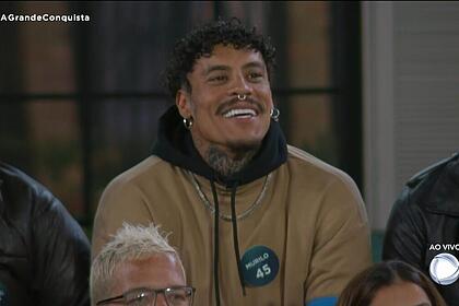 Murilo de camisa bege, sorrindo, comemorando o resultado da votação de A Grande Conquista
