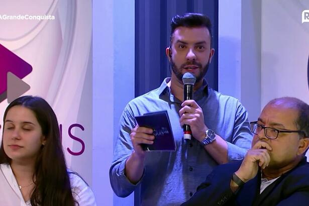 Gilson Silveira, gerente de comunicação da Record, ao lado do logo do PlayPlus na coletiva de imprensa do A Grande Conquista