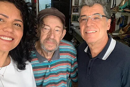Paulo Betti sorrindo ao lado do irmão e esposa