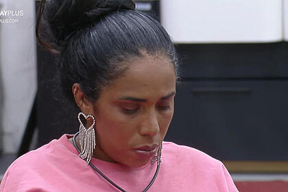 Janielle Nogueira, de cabeça baixa, sentada na mesa de refeição do A Grande Conquista