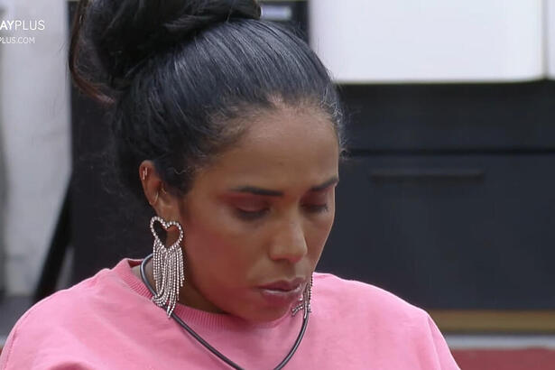 Janielle Nogueira, de cabeça baixa, sentada na mesa de refeição do A Grande Conquista