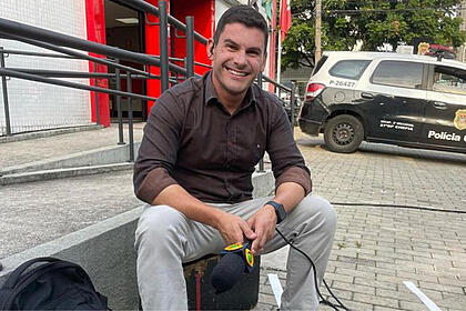 Mark Figueiredo nos bastidores de uma reportagem, com o microfone da Band em mãos