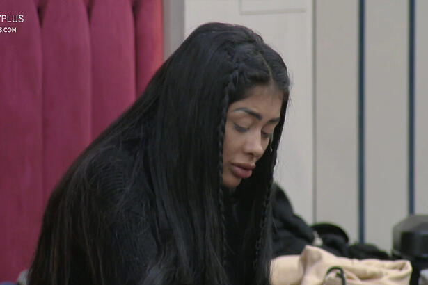Medrado de cabeça baixa, cabelo solto, sentada na cama enquanto conversa com Murilo e Ricardo