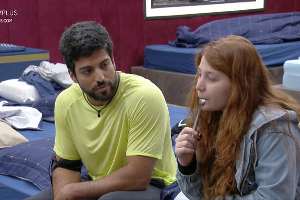 Ricardo Villardo e Giulia Garcia sentados na cama conversando sobre Zona de Risco