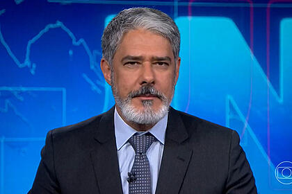 William bonner com semblante sério na bancada do jornal nacional