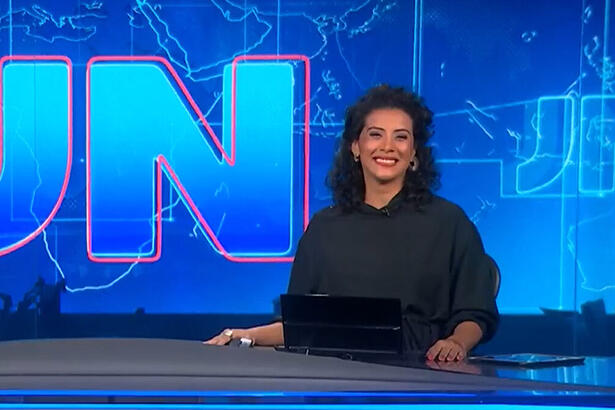 Aline Midlej sorrindo, na bancada do Jornal Nacional, ainda grávida de sua filha Celeste
