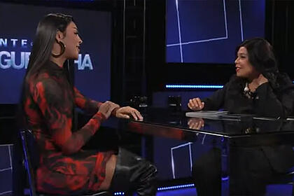 Pabllo Vittar de vestido, sentada, em frente a Blogueirinha