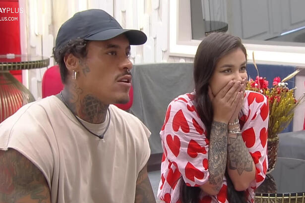 Victoria Macan e Murilo Dias sentados e assistindo ao vídeo dos Donos da Mansão