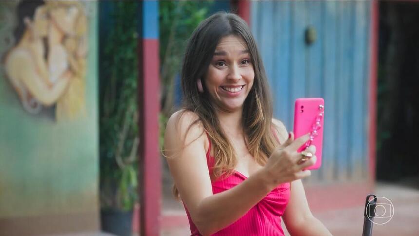 Berenice em cena de Terra e Paixão segurando o telefone que filma Luigi enquanto grita Attenzione Pickpocket