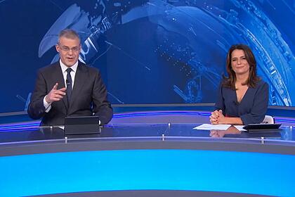 Eduardo Oinegue apontando para a câmera enquanto Adriana Araújo sorrir no encerramento do Jornal da Band desta terça-feira, 11/07/2023