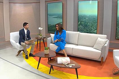 Apresentadores do Jornal do Almoço Cristina Ranzolin e Marco Matos sentados no sofá do telejornal da afiliada da TV Globo