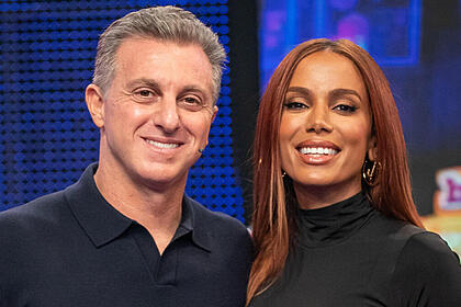 Anitta e Luciano Huck abraçados no palco do Domingão