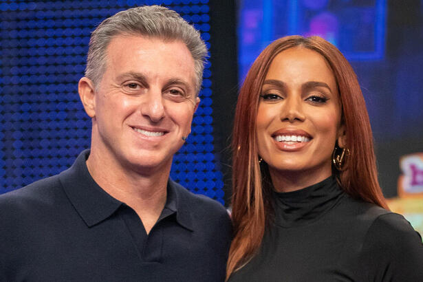 Anitta e Luciano Huck abraçados no palco do Domingão