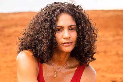 Barbara Reis de regata vermelha, colar de brilhante, cabelo solto, caracterizada como Aline, durante gravação de Terra e Paixão, da TV Globo