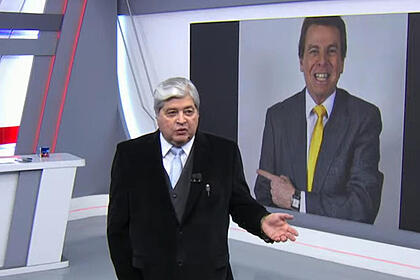 Datena no Brasil Urgente, com uma imagem de Nelson Rubens no telão ao fundo