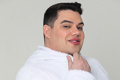 Erick Ricarte sorrindo, de camisa branca, com a mão no queixa