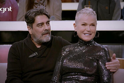 Junno e Xuxa sentados no sofá, em trecho de participação no Sobre Nós Dois