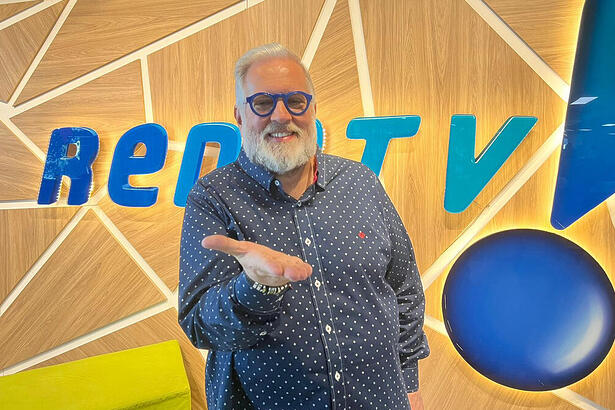 Leão Lobo posando em frente ao logo da RedeTV!