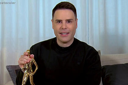 Luiz Bacci segurando uma estátua de ouro em entrevista ao Domingo Espetacular