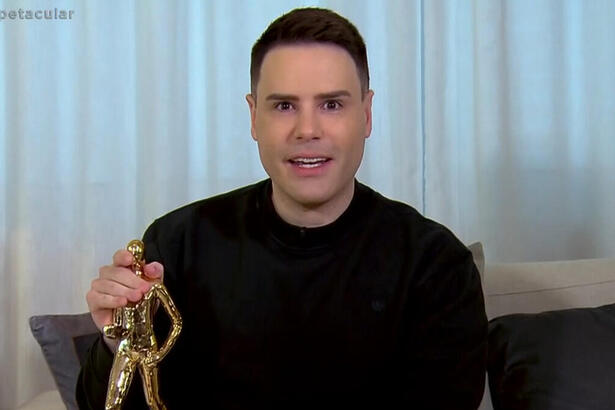 Luiz Bacci segurando uma estátua de ouro em entrevista ao Domingo Espetacular