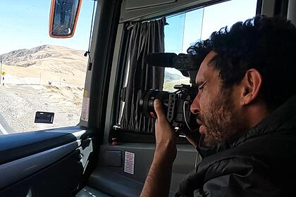 Cinegrafista registrando na frente do ônibus a estrada da viagem, em trecho do Profissão Repórter