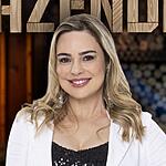 Rachel Sheherazade de top preto e um terninho branco. Ela está sorrindo e com a mão esquerda na cintura, na divulgação de A Fazenda 15