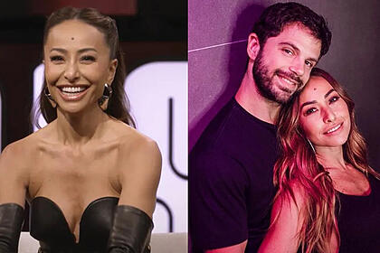 Sabrina Sato sorrindo, de cabelo penteado, vestido preto, sentada durante gravação do Sobre Nós Dois; Imagem 2: Duda Nage de camisa preta, sentado no chão, abraçado com Sabrina Sato