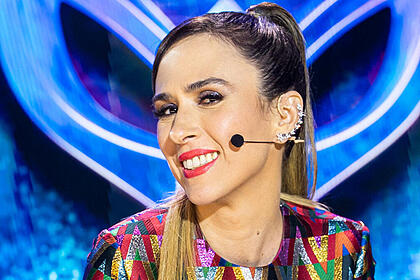 Tatá Werneck sentada na bancada do The Masked Singer Brasil