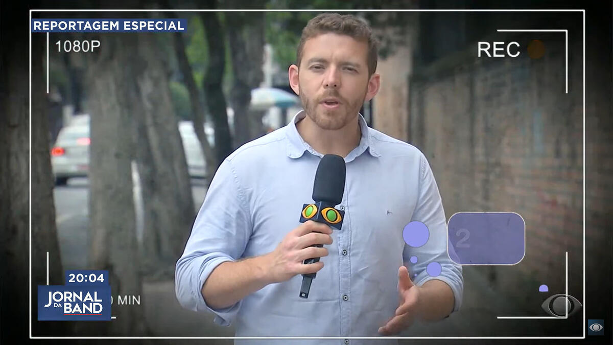 Cesar Cavalcante antes da descoberta do câncer. Ele está com o cabelo grande e segura o microfone da Band