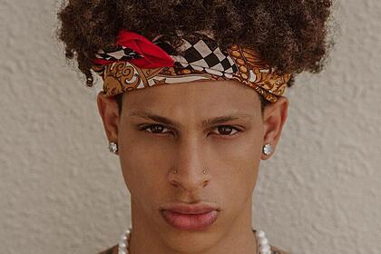 Jeferson Gomes, modelo negro, usa brincos na orelha e um colar com pedras brancas no pescoço