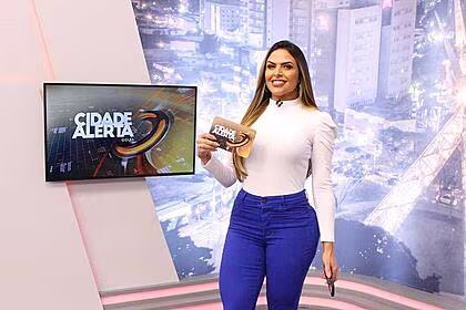 Silvye alves segura a ficha do cidade alerta no cenário do programa na record