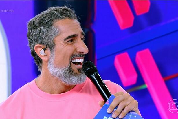 Marcos Mion de camisa rosa e sorrindo no Caldeirão