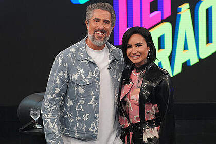 Demi Lovato e Marcos Mion posando abraçados nos bastidores do Caldeirão