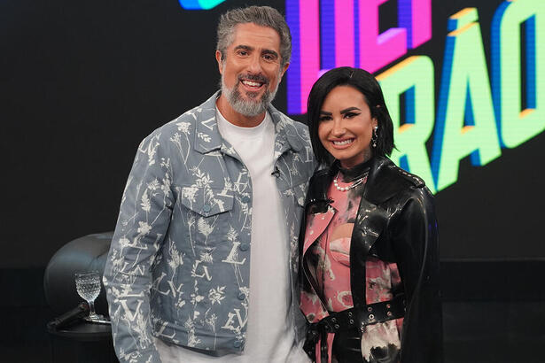Demi Lovato e Marcos Mion posando abraçados nos bastidores do Caldeirão