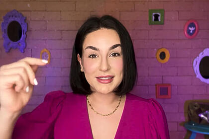 Kéfera de vestido roxo, cabelo curto, gesticulando enquanto grava video pro Youtube