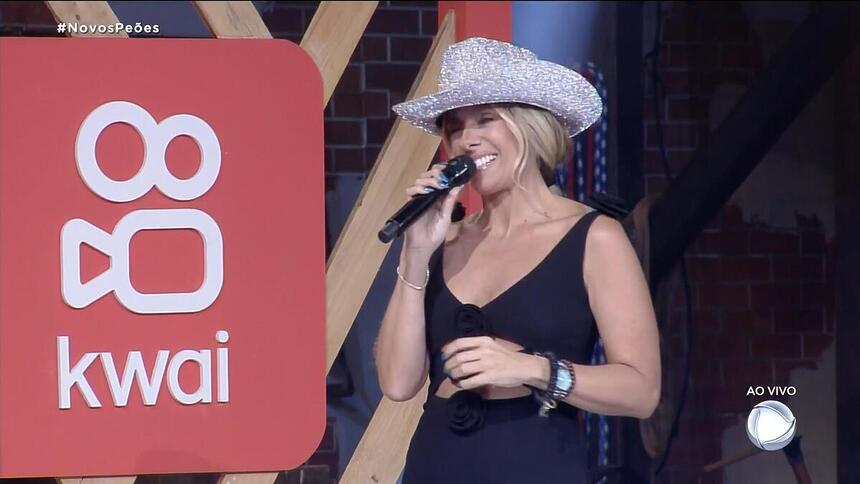 Adriane Galisteu ao lado do logo do Kwai que patrocina a festa de A Fazenda 15