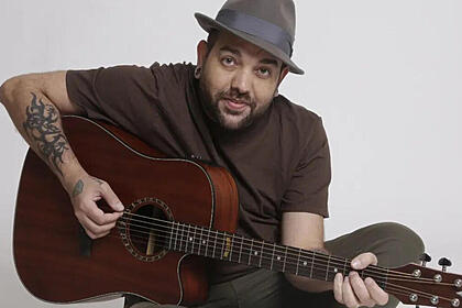 Sander Mecca posando tocando violão