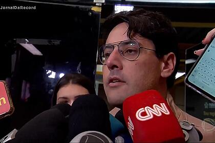 Bruno de Luca é cercado por vários microfones de diversas emissoras de TV na saída da delegacia