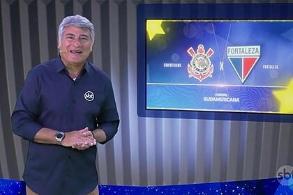 Cleber Machado no estúdio da Copa Sul Americana, na frente de uma tela com o logo do Corinthians e Fortaleza