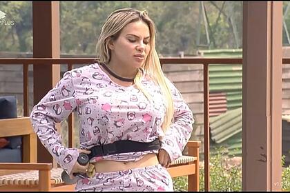 Kally de pijama ajeitando o microfone enquanto conversa com peões na piscina de A Fazenda