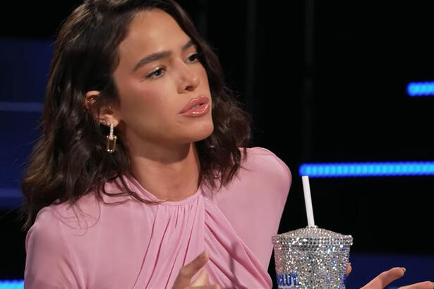 Bruna Marquezine de vestido rosa, sentada, ao lado de um copo personalizado