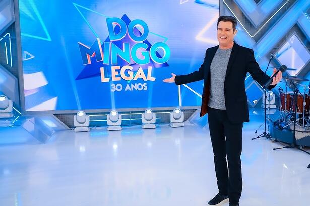 Celso Portiolli sorrindo no cenário do Domingo Legal